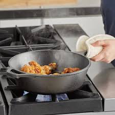 Pre-seasoned cast iron skillet cooking vegetables on stovetop