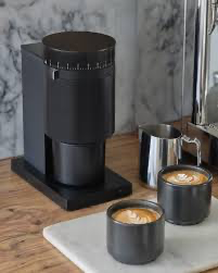 Modern single-dose coffee grinder setup with dosing cup and fresh coffee beans